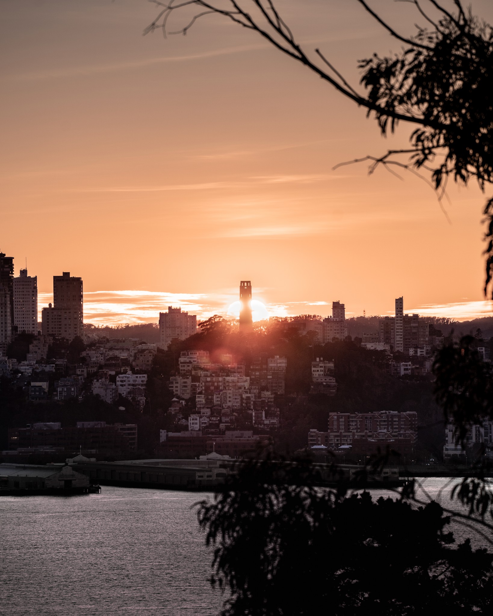 The sun setting directly behind Coit Tower in San Francisco.